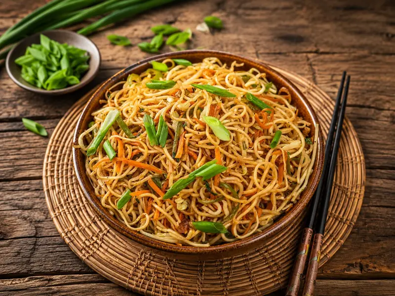 Vegetable hakka noodles with spring onion and chopsticks